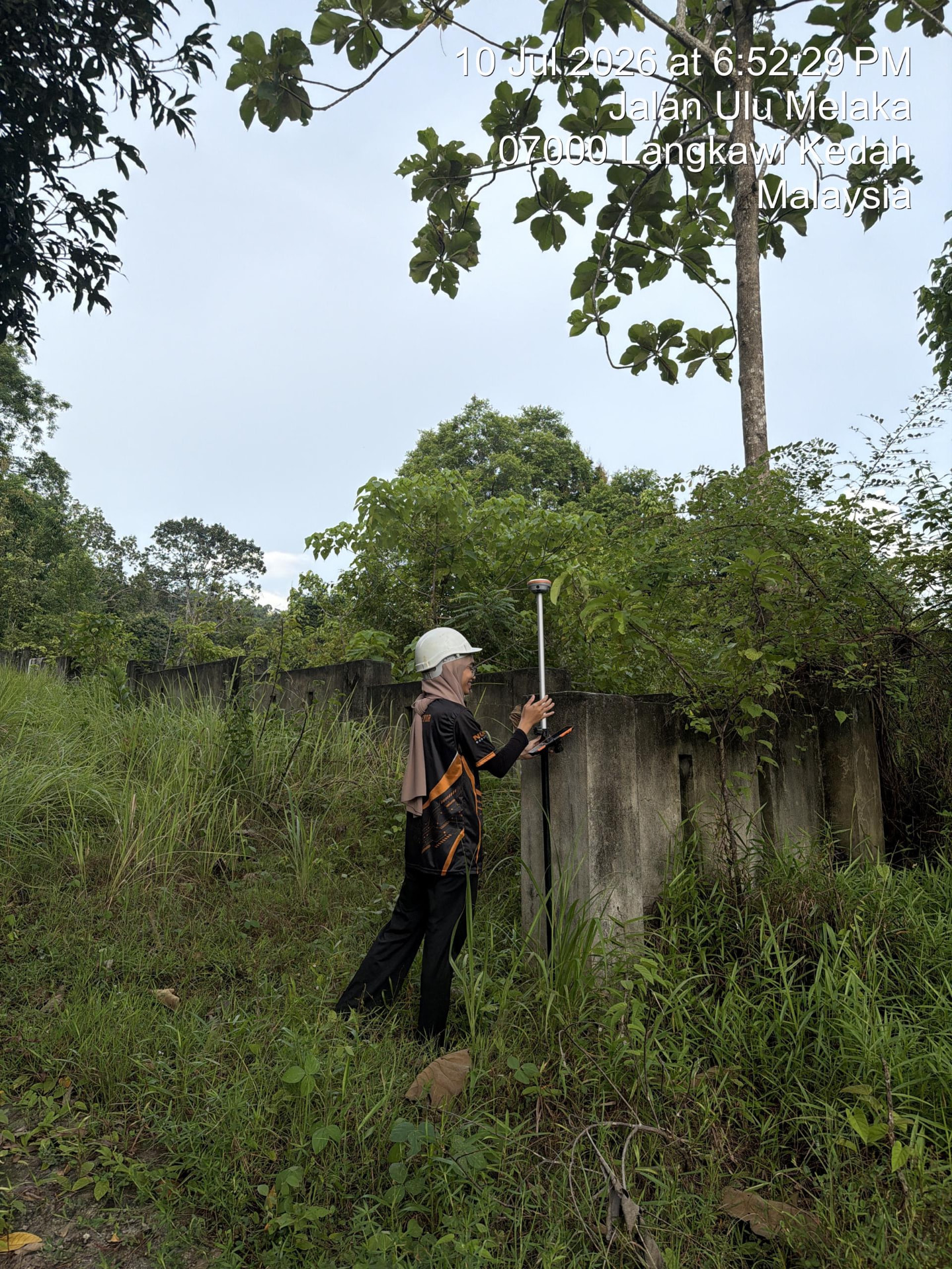 Surveyor taking GPS RTK readings along a concrete fence line in Langkawi, Kedah